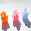 Three colorful 3D-printed crystal clusters in orange, pink, and light blue