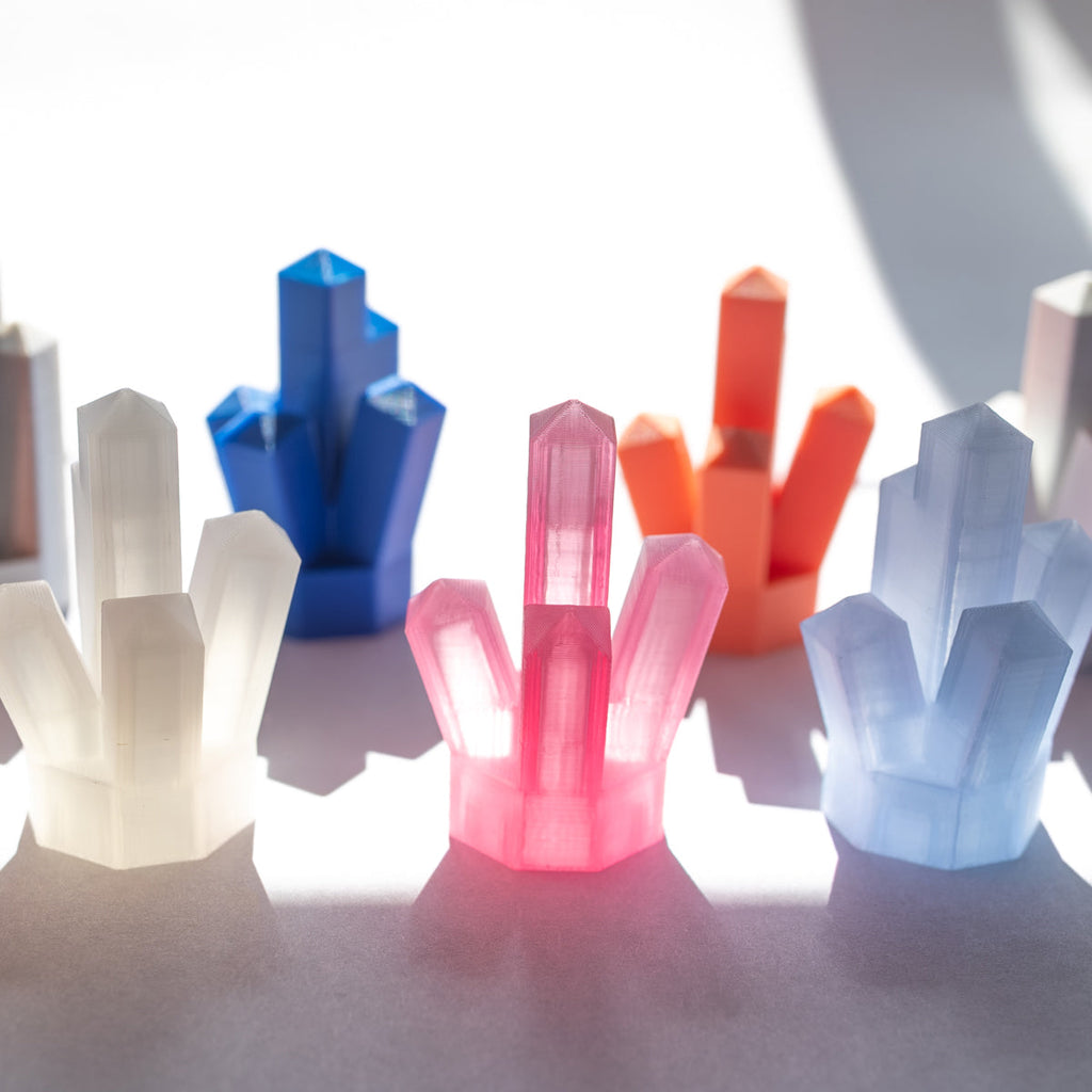 Assorted colorful 3D-printed crystal clusters in sunlight